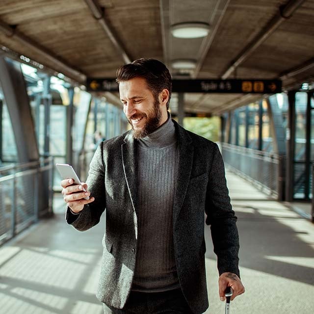 Hombre sonriente enviando usando su celular en la calle